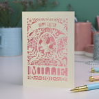 Easter card with laser-cut design featuring a rabbit and floral elements on a desk with stationery items.