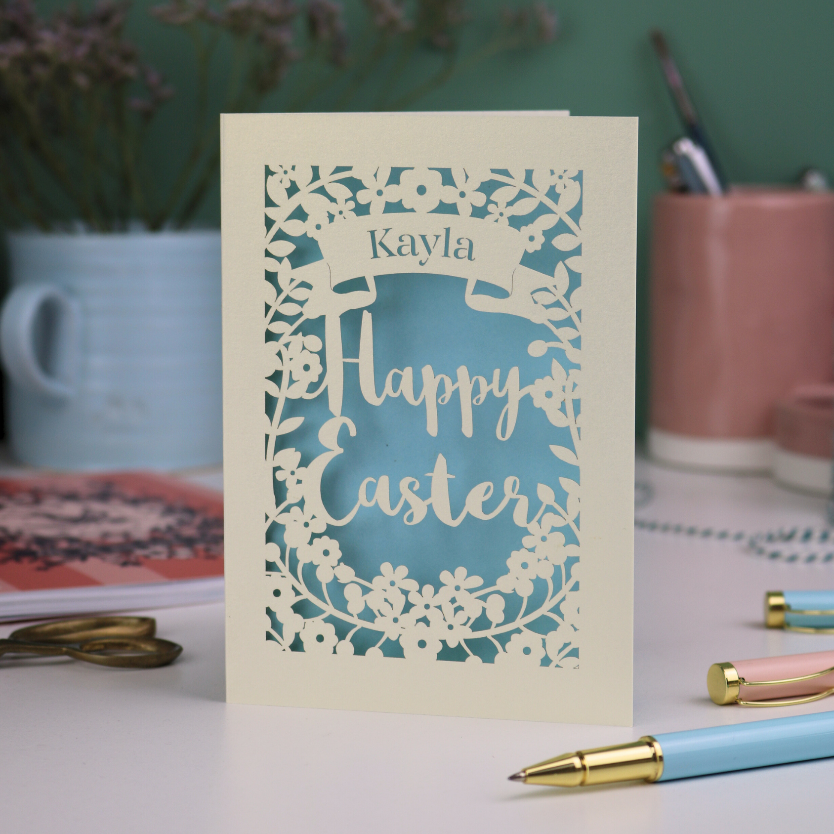 Laser-cut Easter card with 'Happy Easter' text on a desk with stationery items.