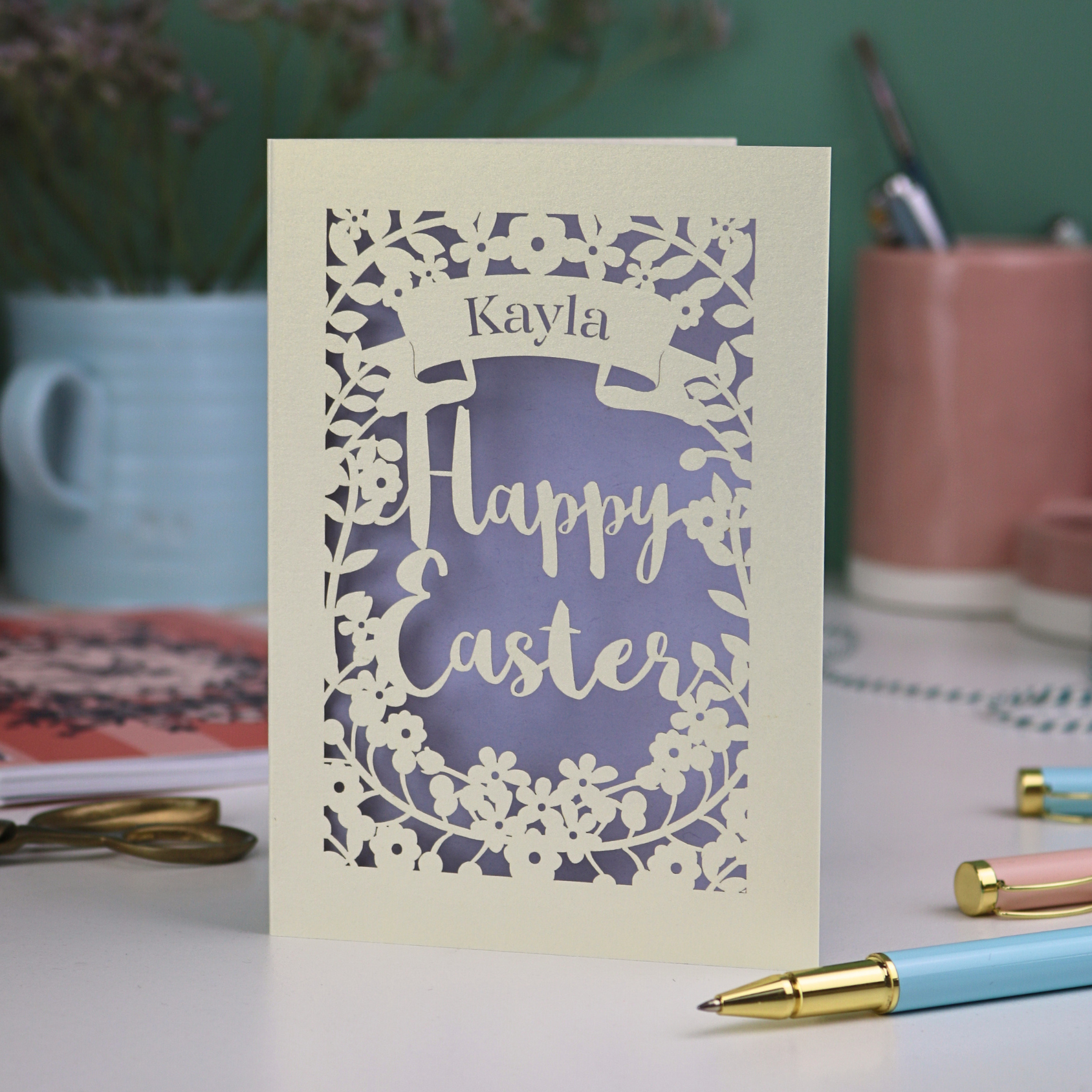 Handmade Easter card with 'Happy Easter' and 'Kayla' text on a desk with stationery items.