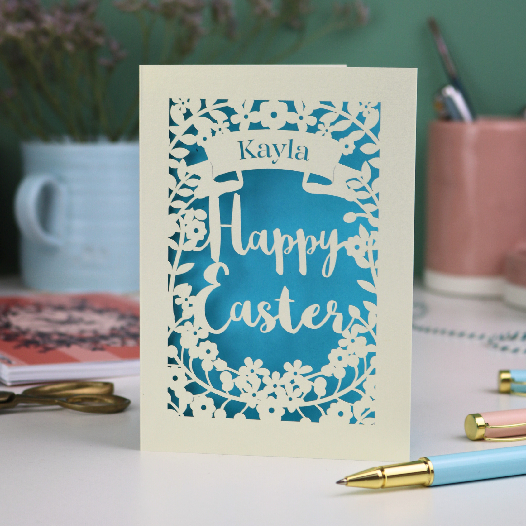 Laser-cut Easter card with 'Happy Easter' text on a desk with stationery 