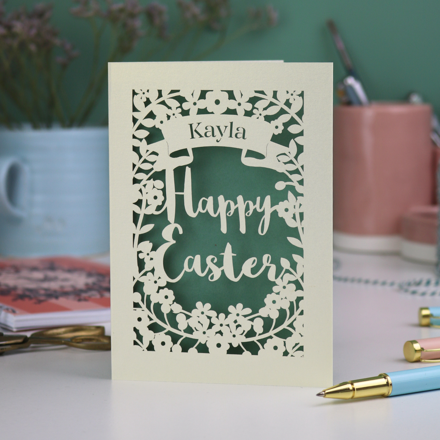 Easter card with 'Happy Easter' and 'Kayla' text on a desk with stationery items.