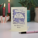 A laser cut get well soon card, with cut out umbrella design and the text 'Sorry you're feeling under the weather, get well soon' and personalised with a name.