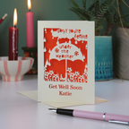 A laser cut get well soon card, with cut out umbrella design and the text 'Sorry you're feeling under the weather, get well soon' and personalised with a name.