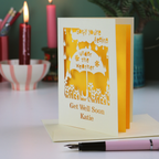 A laser cut get well soon card, with cut out umbrella design and the text 'Sorry you're feeling under the weather, get well soon' and personalised with a name.