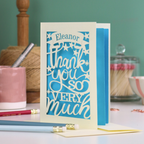 A cream laser cut thank you card with personalised name at the top in a banner, over text 'thank you so very much'