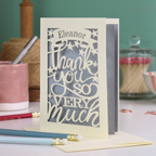 A cream laser cut thank you card with personalised name at the top in a banner, over text 'thank you so very much'