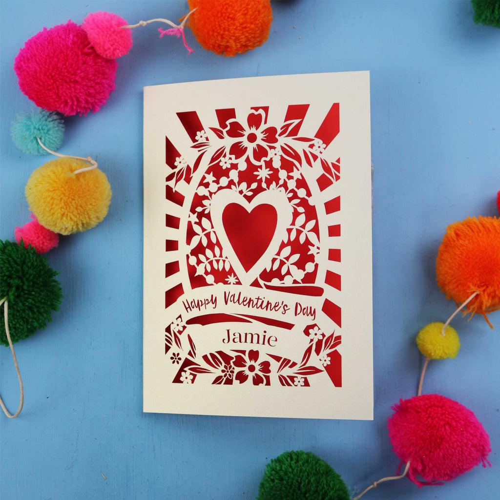 Keepsake Valentine's card with floral heart design on a blue background with colourful pom-poms.