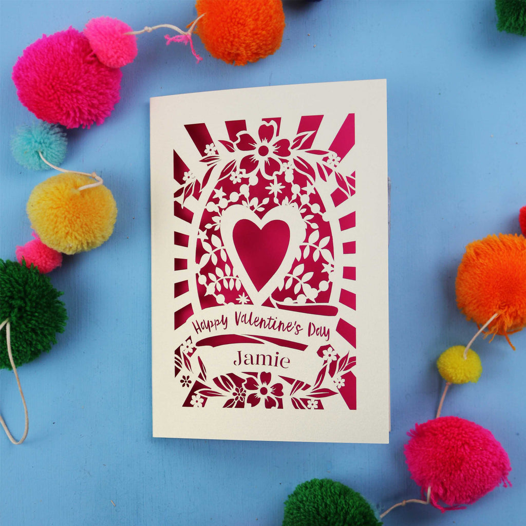 Decorative personalised Valentine's card with floral heart design on a blue background with colourful pom-poms.