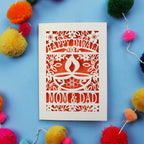 Decorative Diwali card with 'Happy Diwali' and 'Mom & Dad' text on a blue background with colourful pom-poms.