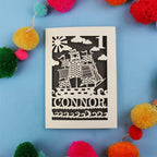 Decorative 1st Birthday card with pirate ship design and 'CONNOR' text on a blue background with colourful pom-poms.