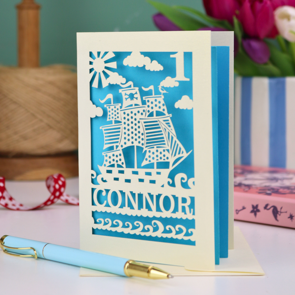 A laser cut 1st birthday card personalised with a name and age, and featuring a cut out pirate ship design