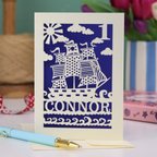 A laser cut 1st birthday card personalised with a name and age, and featuring a cut out pirate ship design in cream on a violet background