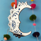 A silver and blue crescent moon Christmas tree ornament