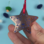 A rose gold metal and enamel Christmas star decoration