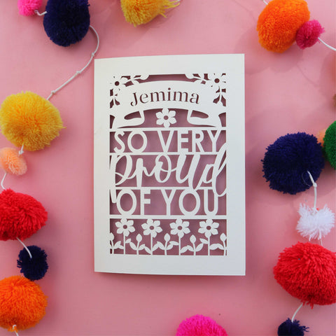 A paper cut celebration card that is personalised with a name and reads "So very proud of you"