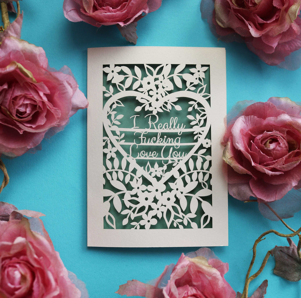 A laser cut Valentine's card that says "I really fucking love you" surrounded by flowers and leaves