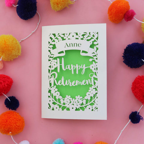 A paper cut card for a happy retirement, personalised with a name in a banner at the top, and the words "Happy Retirement" - A6 / Bright Green