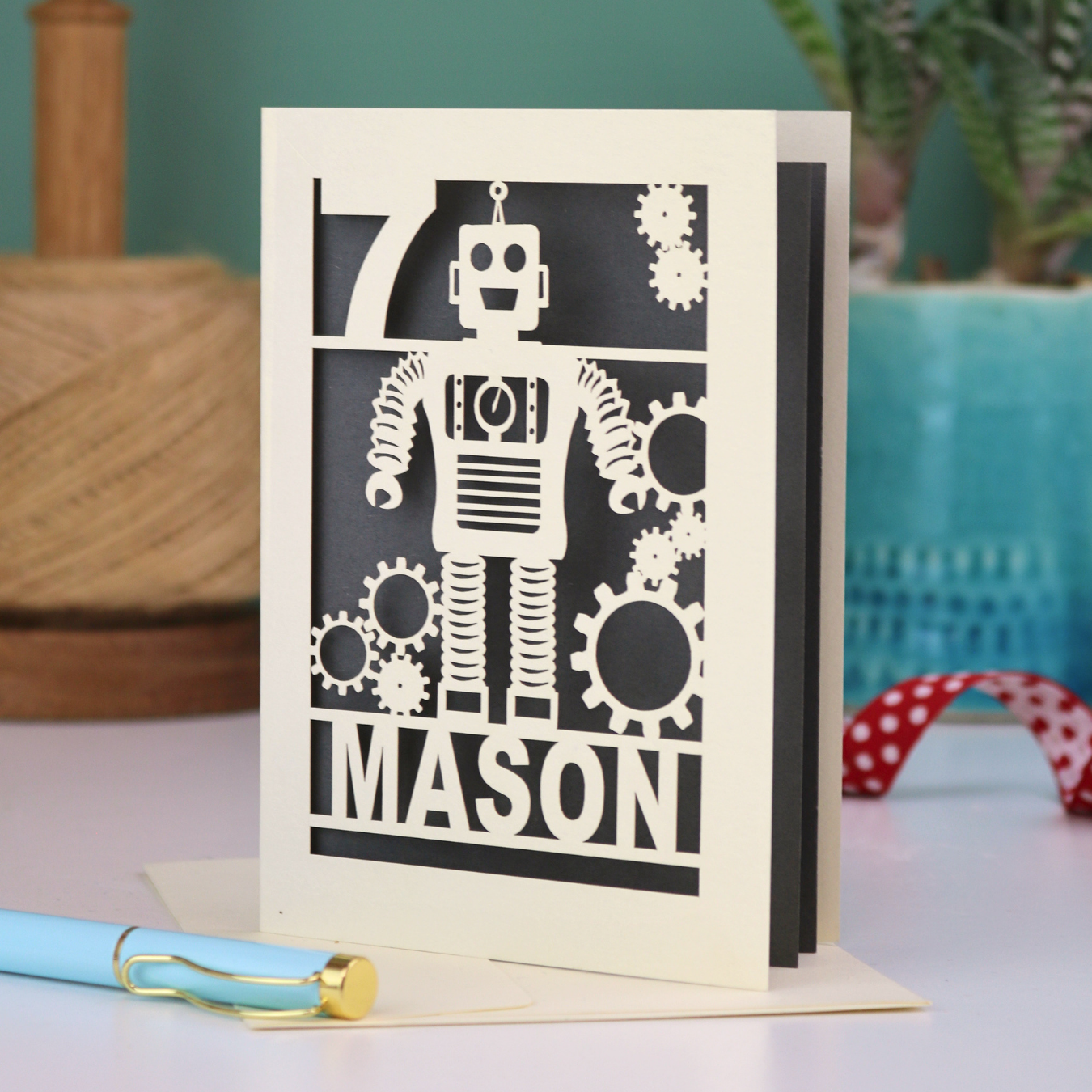 A cream and grey laser cut birthday card with robot design and personalised with the age and name of the recipient