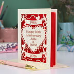 Red and cream 40th anniversary card with decorative elements on a blurred background