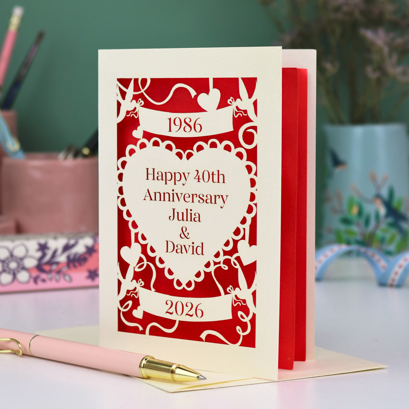 Red and cream 40th anniversary card with decorative elements on a blurred background