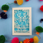 Decorative star sign birthday card with Scorpio symbol and 'EVIE' text on a blue background with colourful pom-poms.