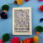 Decorative star sign birthday card with Scorpio symbol and 'EVIE' text on a blue background with colourful pom-poms.