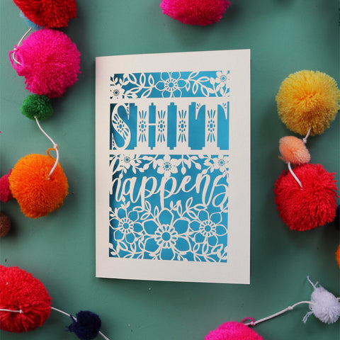 A laser cut card that says "Shit happens" - A5 / Peacock Blue