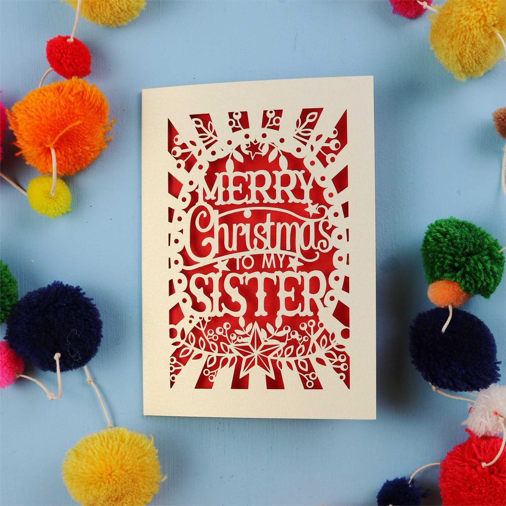 Sister Christmas card with 'Merry Christmas to my sister' text on a blue background with colourful pom-poms.