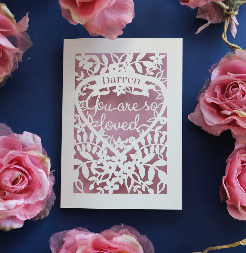 A personalised Valentine's card with cut out details to read "name, you are so loved"
