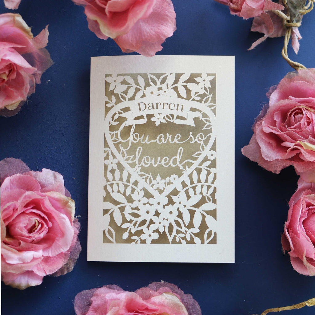 A cut out Valentines card that says "Name, you are so loved"