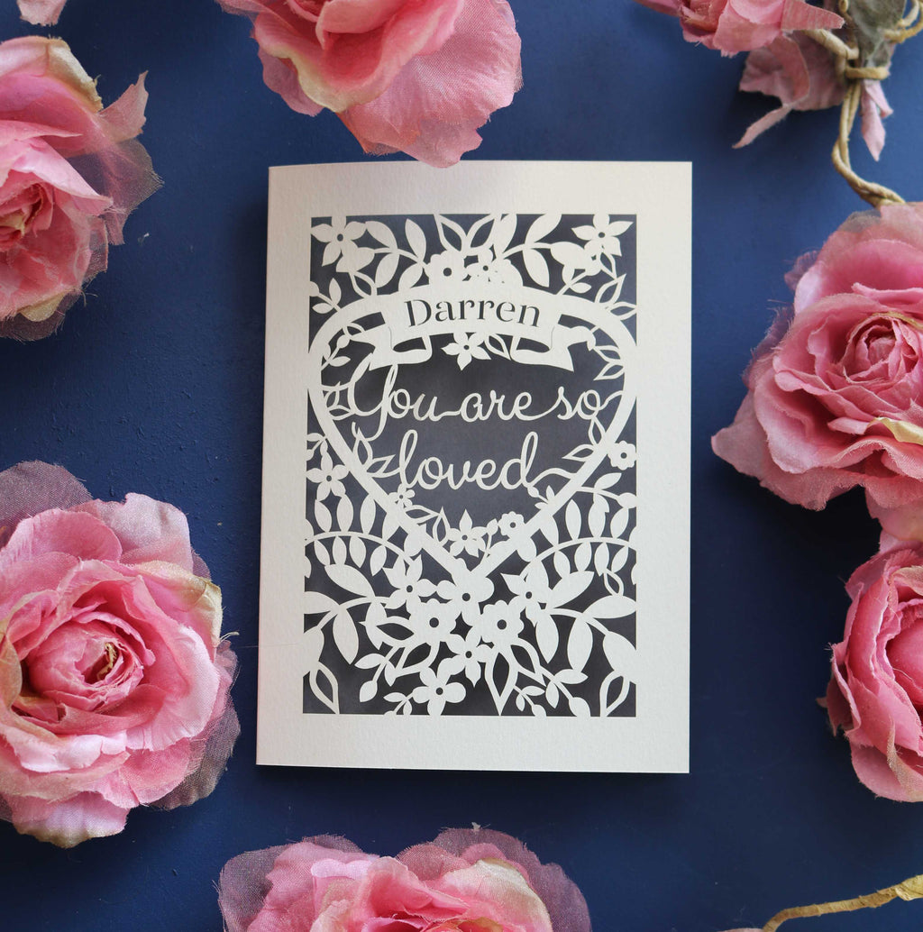 A personalised laser cut Valentines card that says "Name, you are so loved"