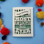 Laser cut Birthday Card with 'Happy Birthday to the most awesome son ever' text on a blue background with colourful pom-poms.