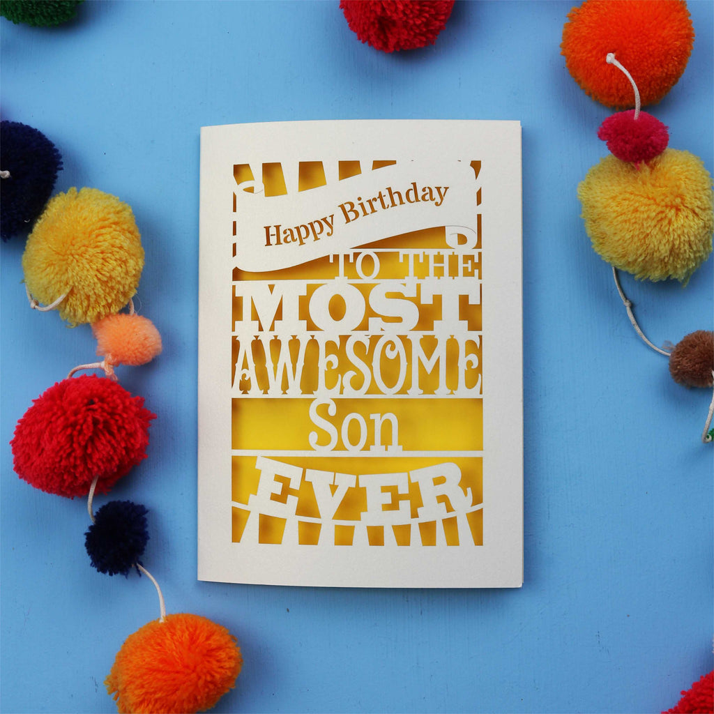 Laser cut Son Birthday Card with 'Happy Birthday to the most awesome son ever' text on a blue background with colourful pom-poms.