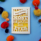 Laser cut Son Birthday Card with 'Happy Birthday to the most awesome son ever' text on a blue background with colourful pom-poms.