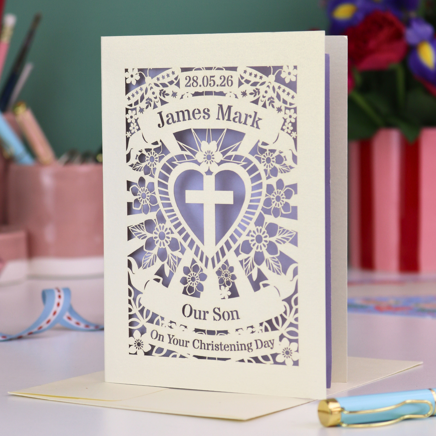 Personalized christening card with decorative design and text on a table.