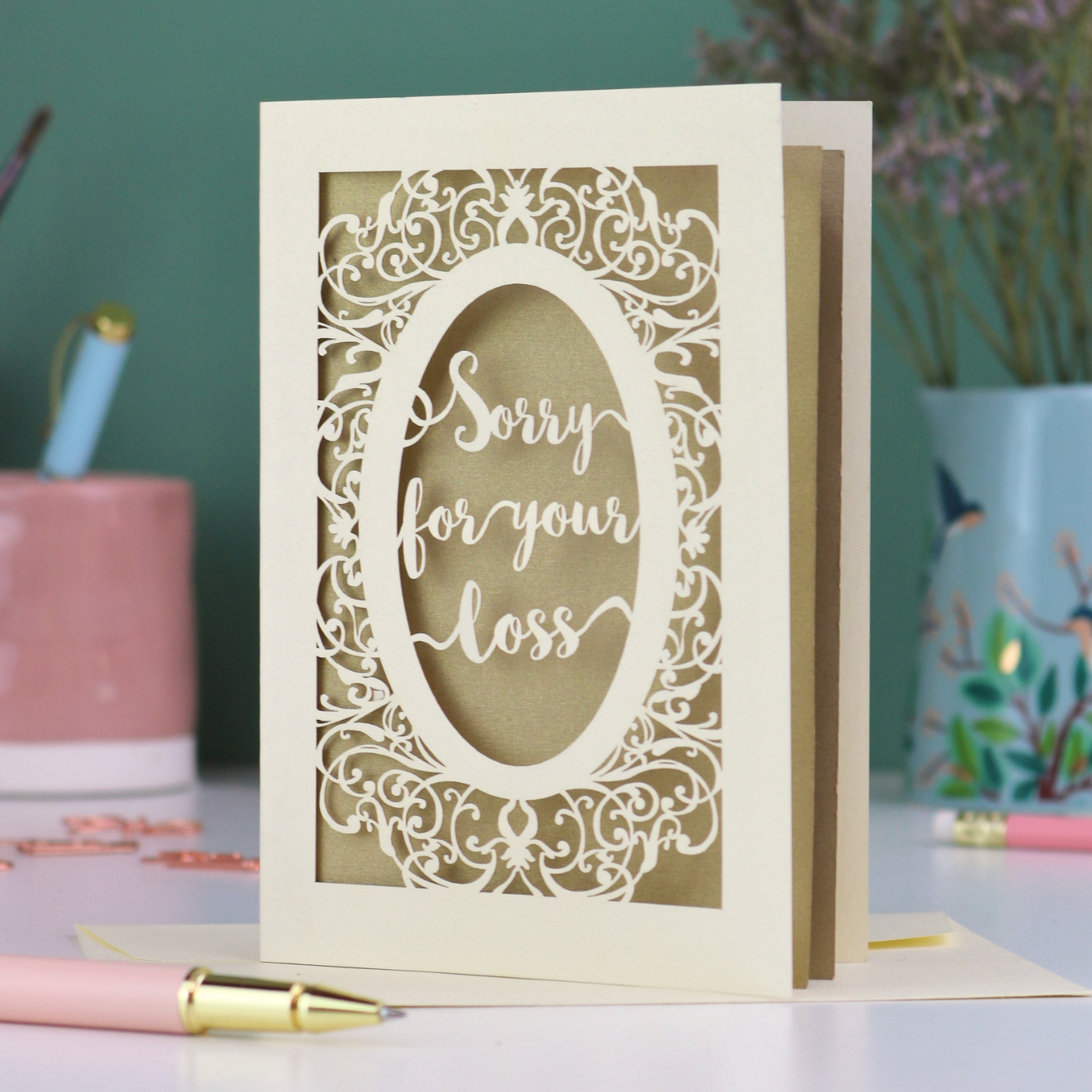 A laser cut sympathy card with "sorry for your loss" text and decorative border
