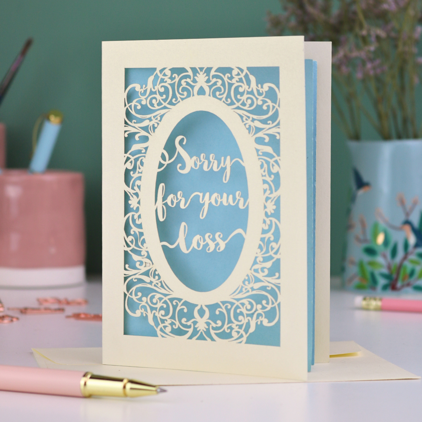 A laser cut sympathy card with "sorry for your loss" text and decorative border