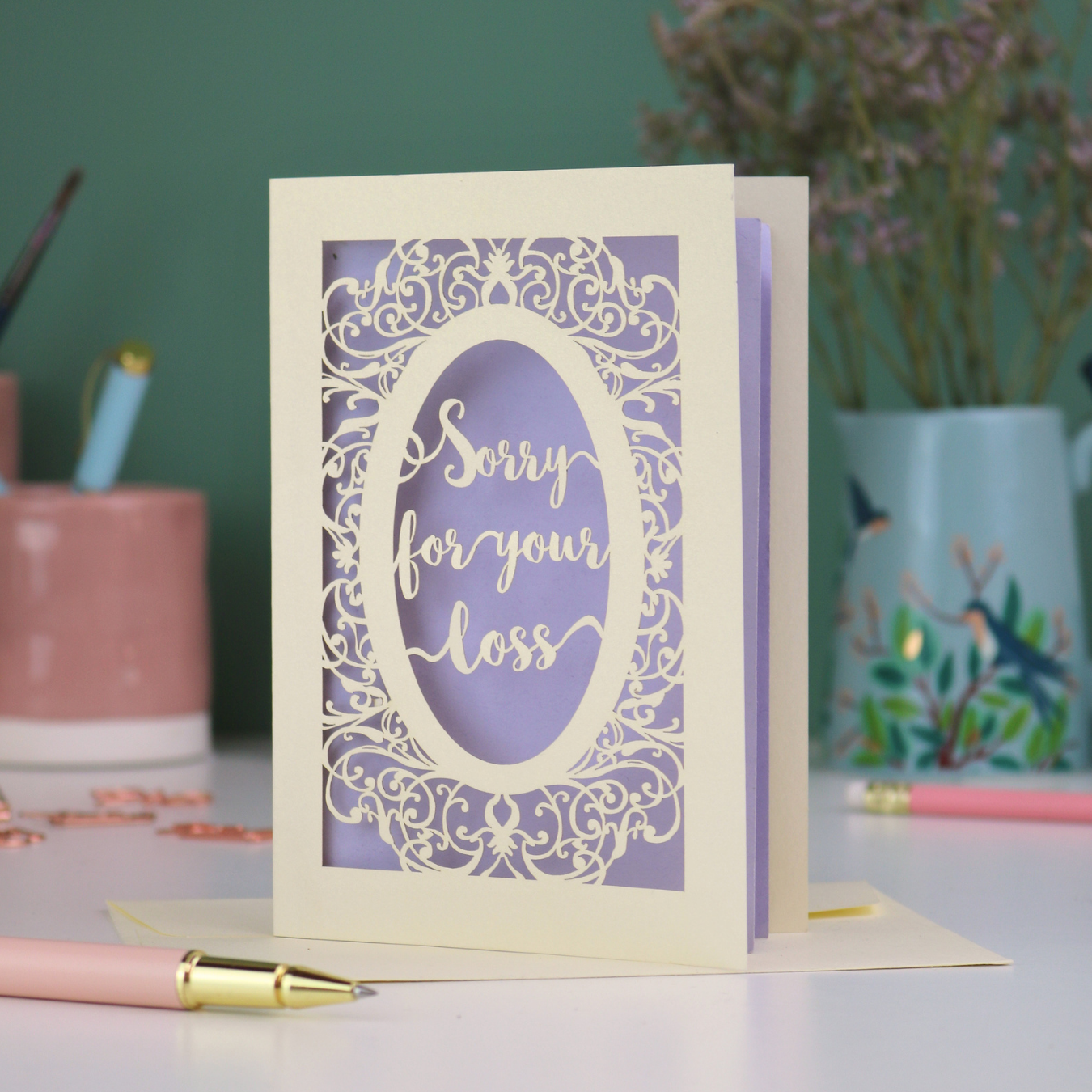 A laser cut sympathy card with "sorry for your loss" text and decorative border