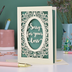A laser cut sympathy card with "sorry for your loss" text and decorative border