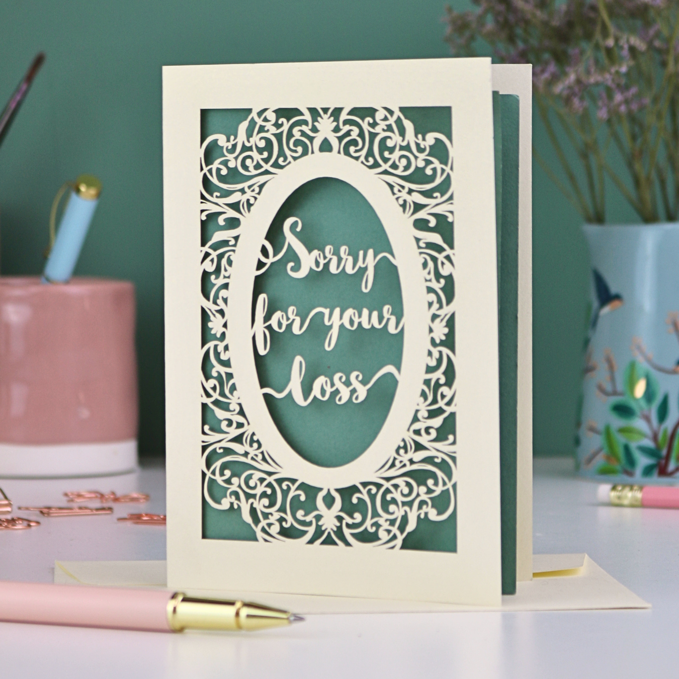 A laser cut sympathy card with "sorry for your loss" text and decorative border