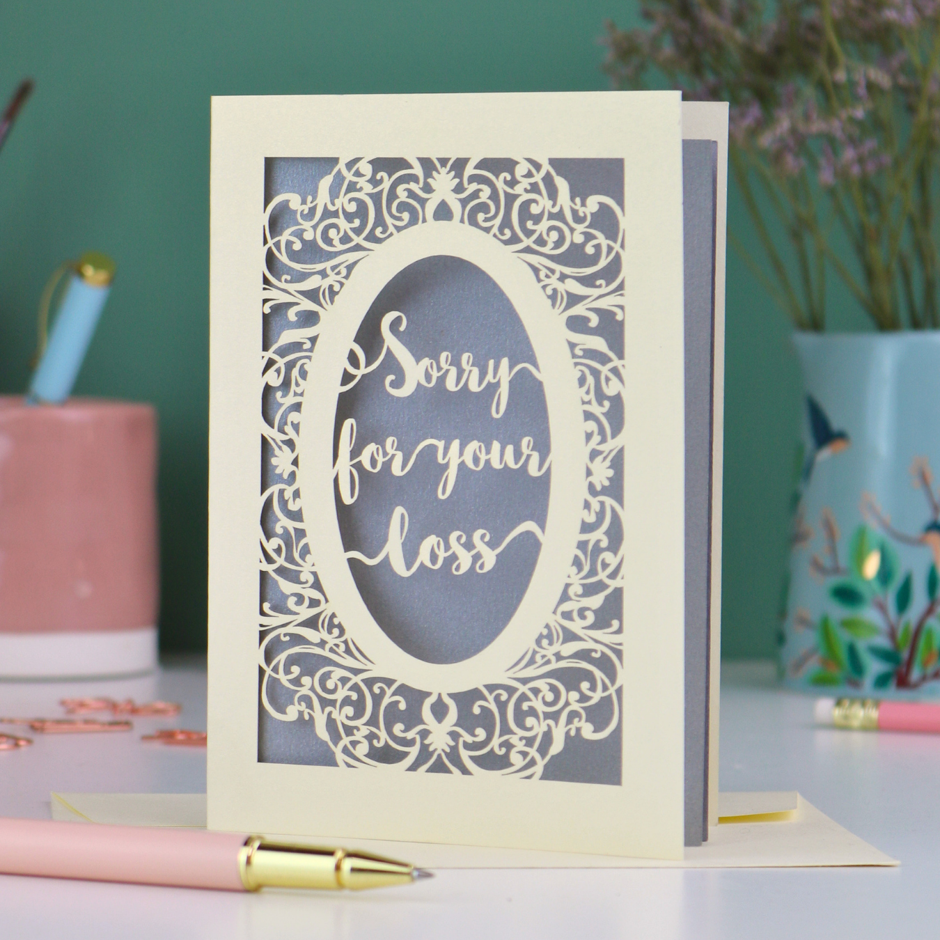 A laser cut sympathy card with "sorry for your loss" text and decorative border