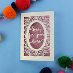 Luxury Sympathy Card with 'Sorry for your loss' text laser cut from cream card with a dusky pink paper backing, on a blue background.