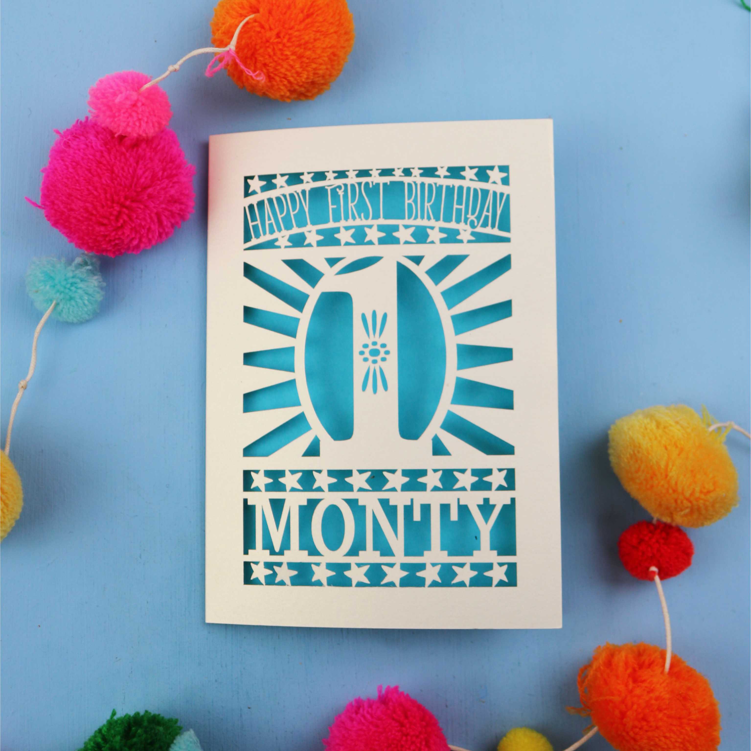 A laser cut first birthday card featuring a cut out '1' design, the words "Happy First Birthday" and personalised with a name.