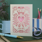 Decorative Step-mum Mother's Day card with floral design and text 'You're just like a mum to me' on a green surface with a pen and mug in the background.