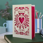 Decorative Step-mum Mother's Day card with floral design and text 'You're just like a mum to me' on a green surface with a pen and mug in the background.