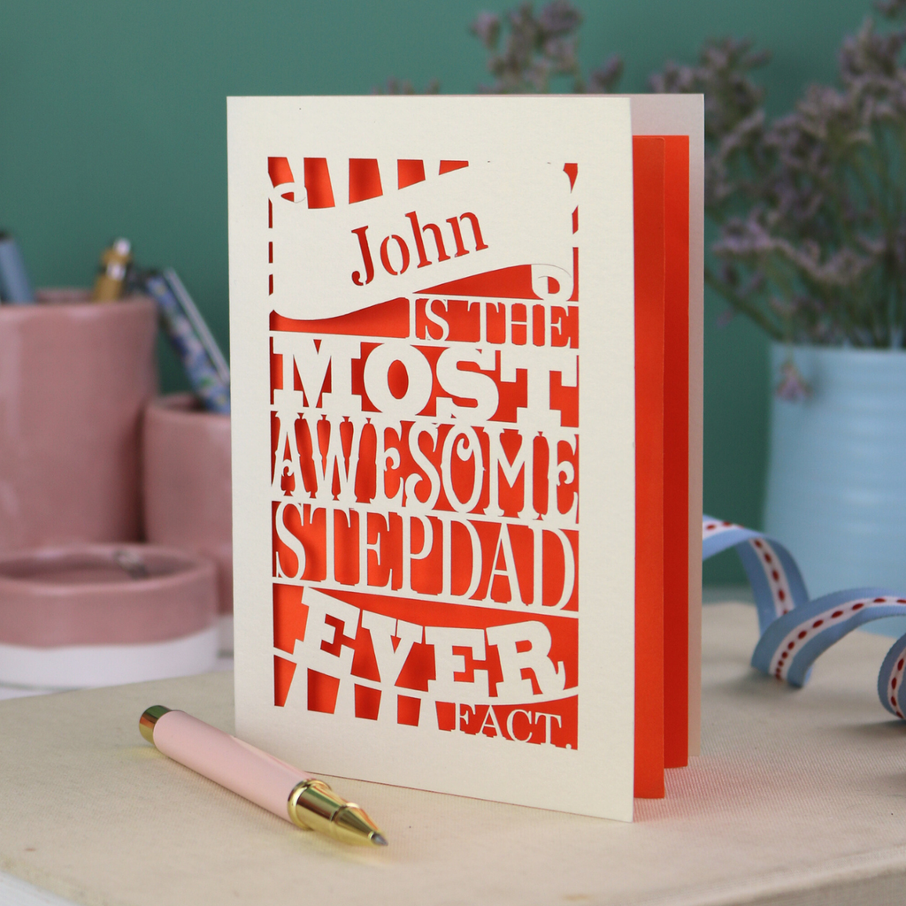 Laser cut Step-dad Card with personalized text, "John is the most awesome stepdad ever. Fact." on a table with decorative items