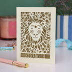 A laser cut greetings card based on the Strength tarot card, with cut out lion design and the word "Strength" 