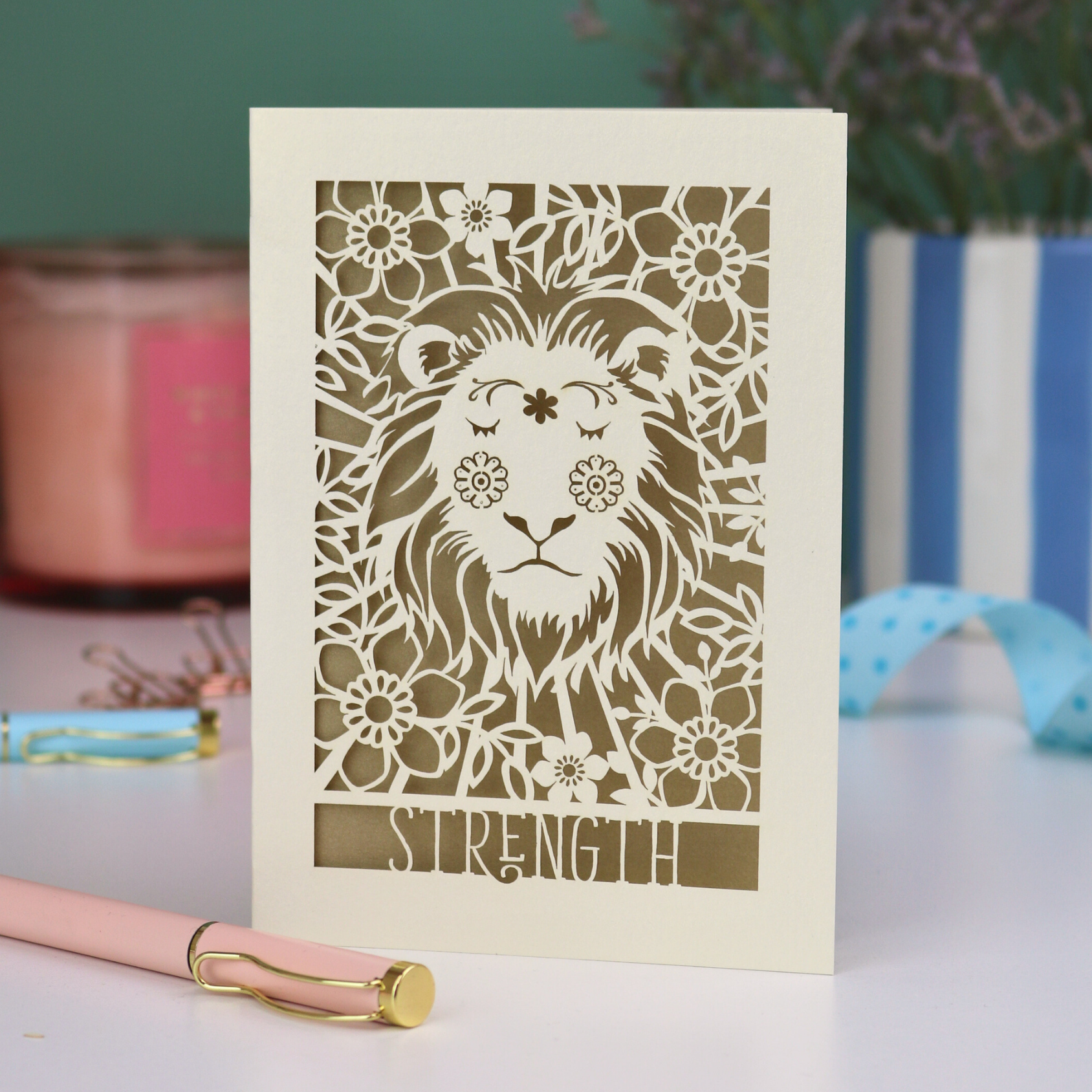 A laser cut greetings card based on the Strength tarot card, with cut out lion design and the word "Strength" 