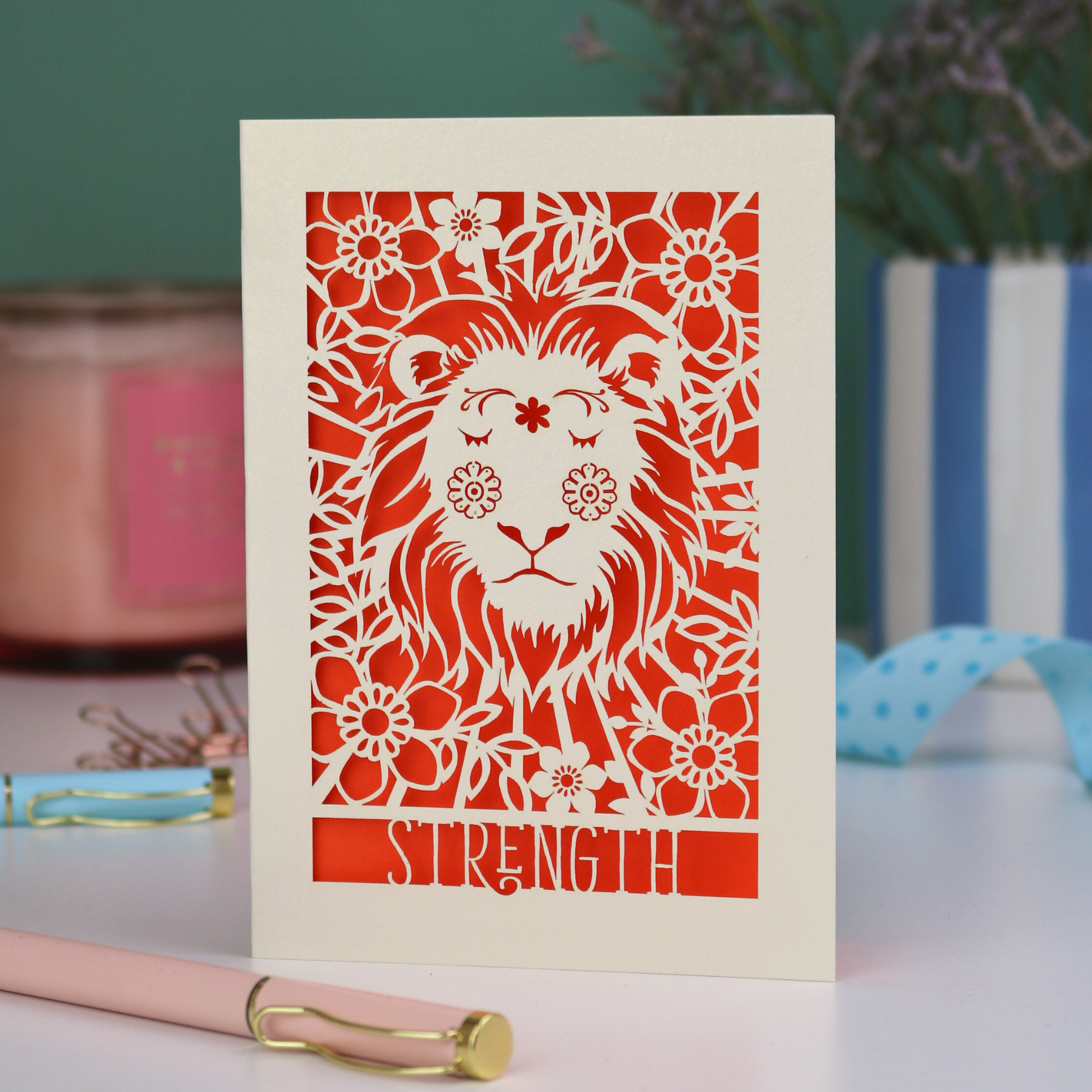 A laser cut greetings card based on the Strength tarot card, with cut out lion design and the word "Strength" 
