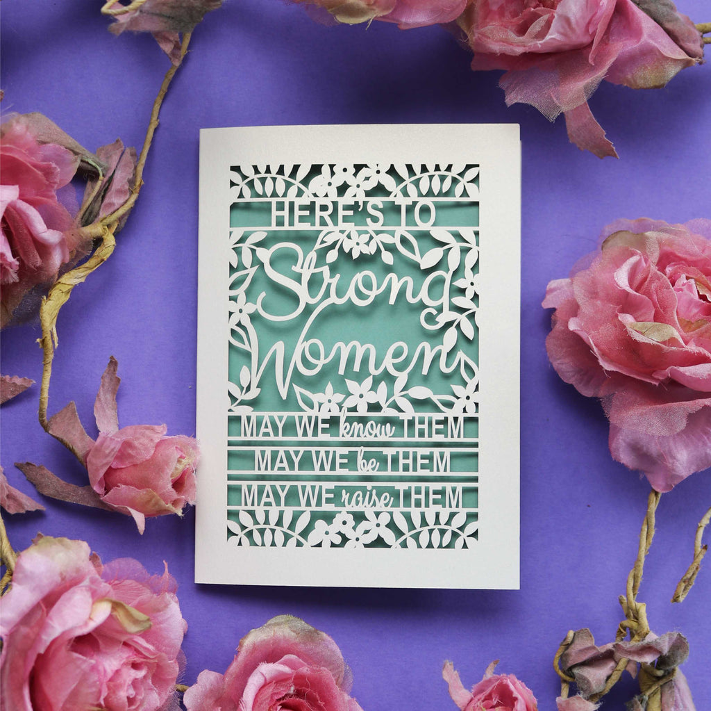 A laser cut sisterhood Card that says "Here's to Strong Women, may we know them, may we be them, may we raise them"